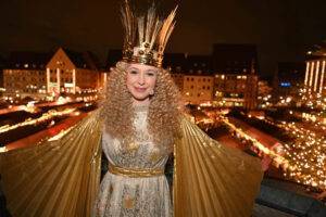 Frau als goldener Engel bekleidet vor der festlichen Stimmung des Nürnberger Christkindlmarktes